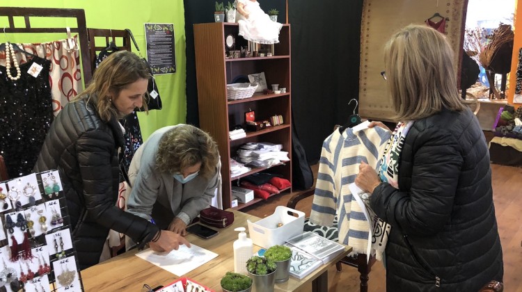 Charo Blanco con dos voluntarias explicando todos los pormenores de la tienda