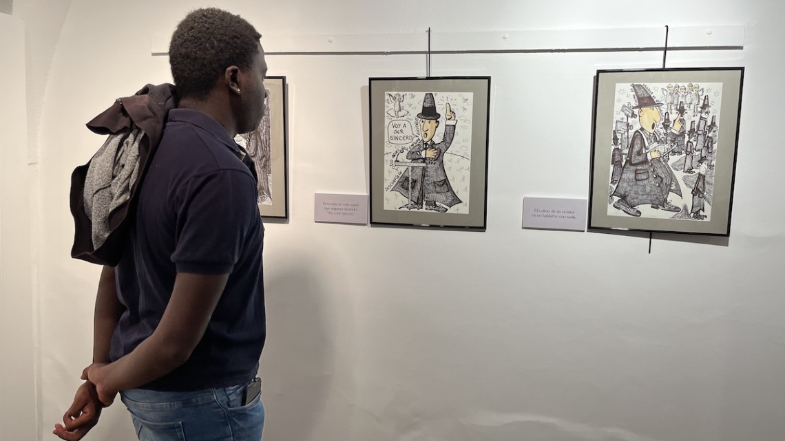 Una persona viendo la exposición de dibujos de Juan Bautista Escribano Cabrera basada en las hilariadas