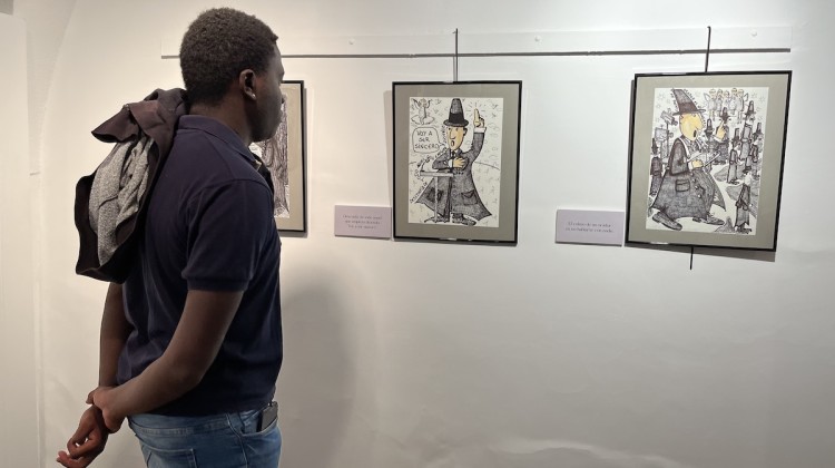 Una persona viendo la exposición de dibujos de Juan Bautista Escribano Cabrera basada en las hilariadas