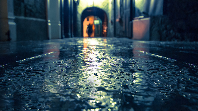 Focus on wet ground along dark medieval alley on a rainy night, Butter Slip, Kilkenny Ireland.