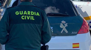 Un agente de la Guardia Civil junto a un vehículo oficial.