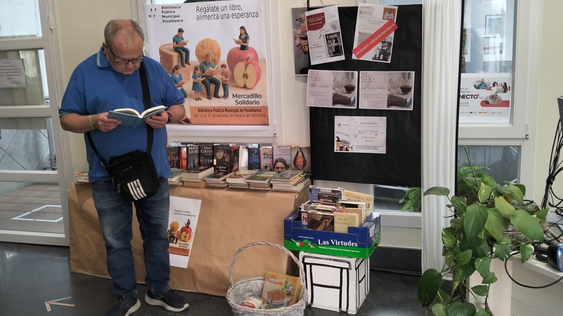 Un usuario ojea los libros que se regalan a cambio de un alimento no perecedero.